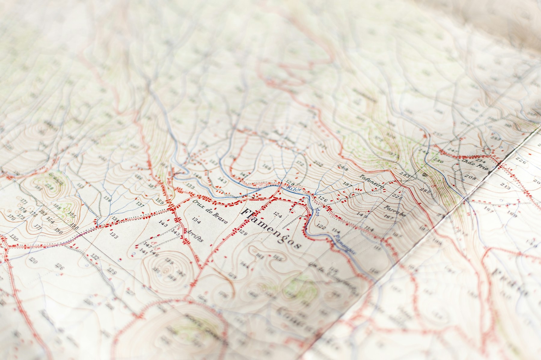 Carte topographique dépliée : courbes de niveau, cours d’eau et routes tracées en rouge.